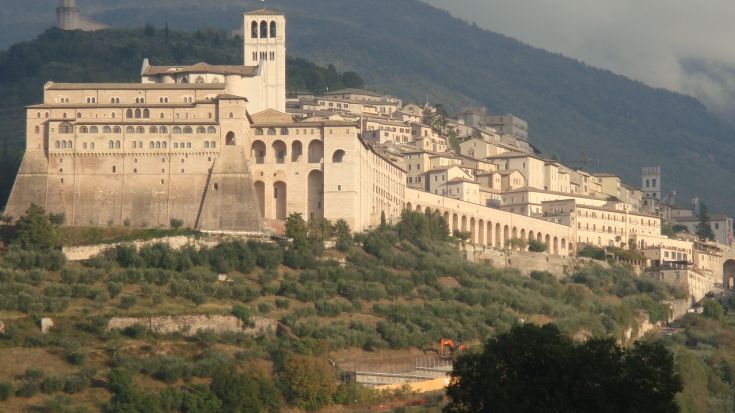 Un panorama dell'abbazia in Umbria, circondata da verdi colline e un cielo leggermente nuvoloso. Un luogo carico di storia e spiritualità.