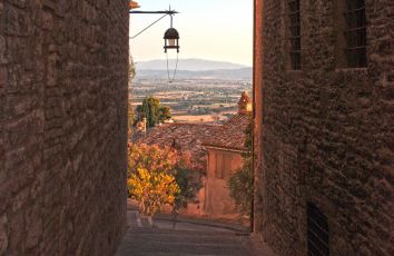 Una scena tranquilla tra le strade di un antico borgo, circondata da un paesaggio verdeggiante.