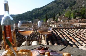 Due bicchieri di vino rosé e una bottiglia, accompagnati da stuzzichini su un tavolo all'aperto.