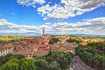 Panorama della città umbra con tetti in terracotta e un cielo sereno.