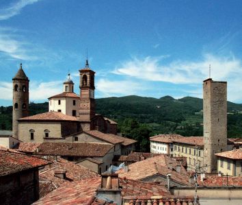 Panorama di un villaggio umbro con torri e una cattedrale, circondato da colline verdi.