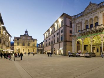 Piazza illuminata dalla luce serale, circondata da palazzi storici, ideale per passeggiate e attività all'aperto.