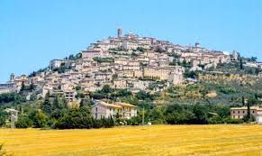 Un panorama di un antico borgo situato su una collina, circondato da campi di grano dorati.