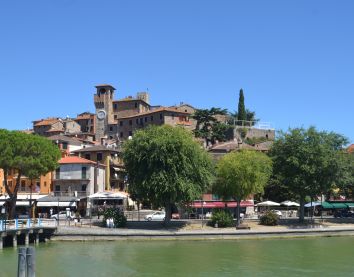 Un piccolo villaggio che si affaccia su un lago tranquillo, con case storiche e un caratteristico campanile.