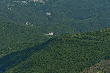 Un panorama di colline verdi e alberi, con un villaggio visibile in lontananza.