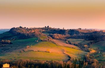 Un panorama delle colline umbre al tramonto, con campi e alberi che si stagliano contro il cielo.