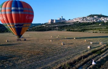 Una mongolfiera si libra sopra i campi umbri, offrendo una scena suggestiva dei borghi storici circostanti.