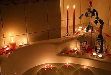 Un'atmosfera intima con candele e petali di rosa in una vasca da bagno.