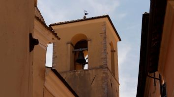 Campanile in un contesto architettonico, con un cielo blu senza nuvole sullo sfondo.