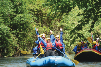 Sorrisi e adrenalina durante un'escursione in rafting tra paesaggi verdi immersi nella natura.