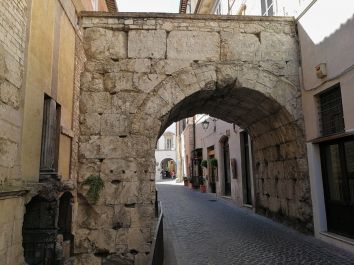 Un semplice arco in pietra che collega le strade di un borgo storico.