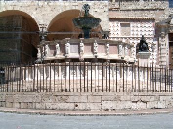 Una fontana situata in una piazza storica, circondata da statue e caratterizzata da elementi architettonici locali.