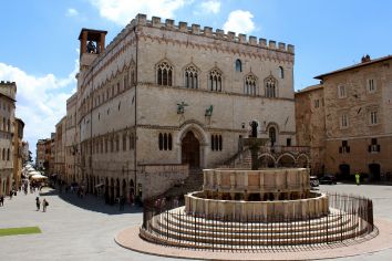 Il Palazzo dei Priori è un'imponente struttura con una fontana centrale circondata da un'atmosfera attiva.