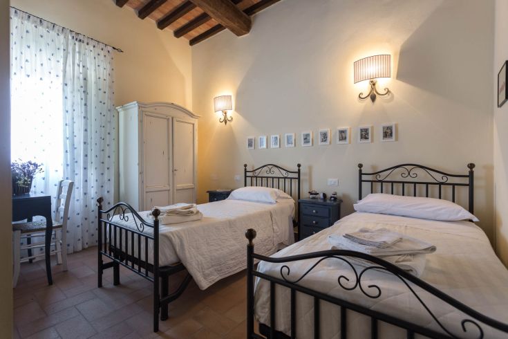 Camera semplice con letti singoli e mobili in legno scuro.