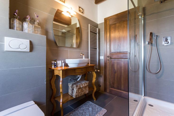 Bagno contemporaneo con lavabo in legno e doccia, caratterizzato da linee semplici e arredi funzionali.