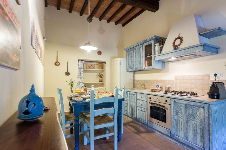 Cucina con mobili blu e particolari rustici, creando un ambiente caldo e familiare.
