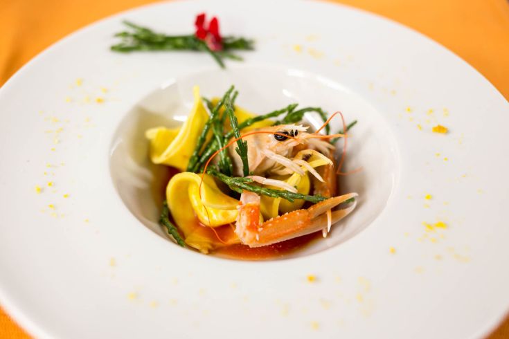 Un piatto di pasta fresca con gamberi e asparagi, presentato su un piatto bianco sobrio.