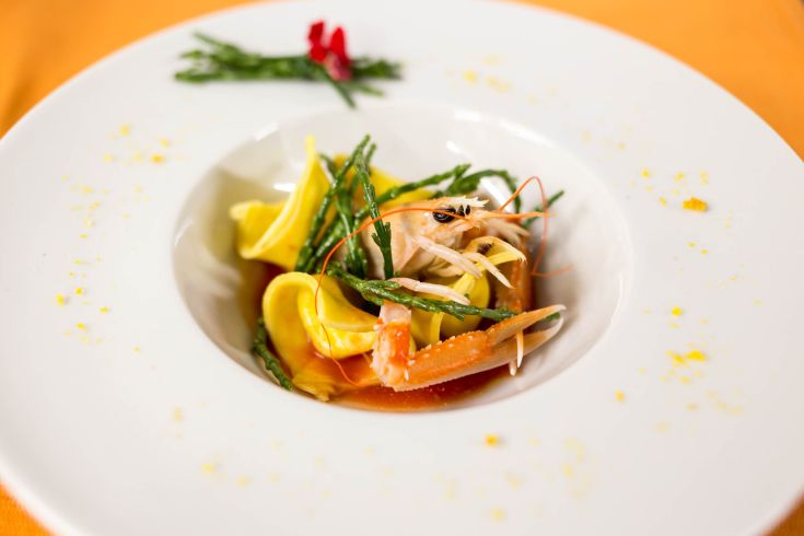 Un piatto di pasta ripiena con gamberi e asparagi, accompagnato da una salsa leggera.