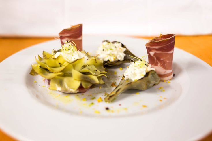 Piatto di carciofi con crema e prosciutto, servito in modo semplice ma invitante.
