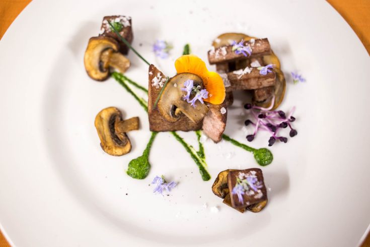 Un piatto raffinato con funghi e fiori commestibili, servito in modo elegante.