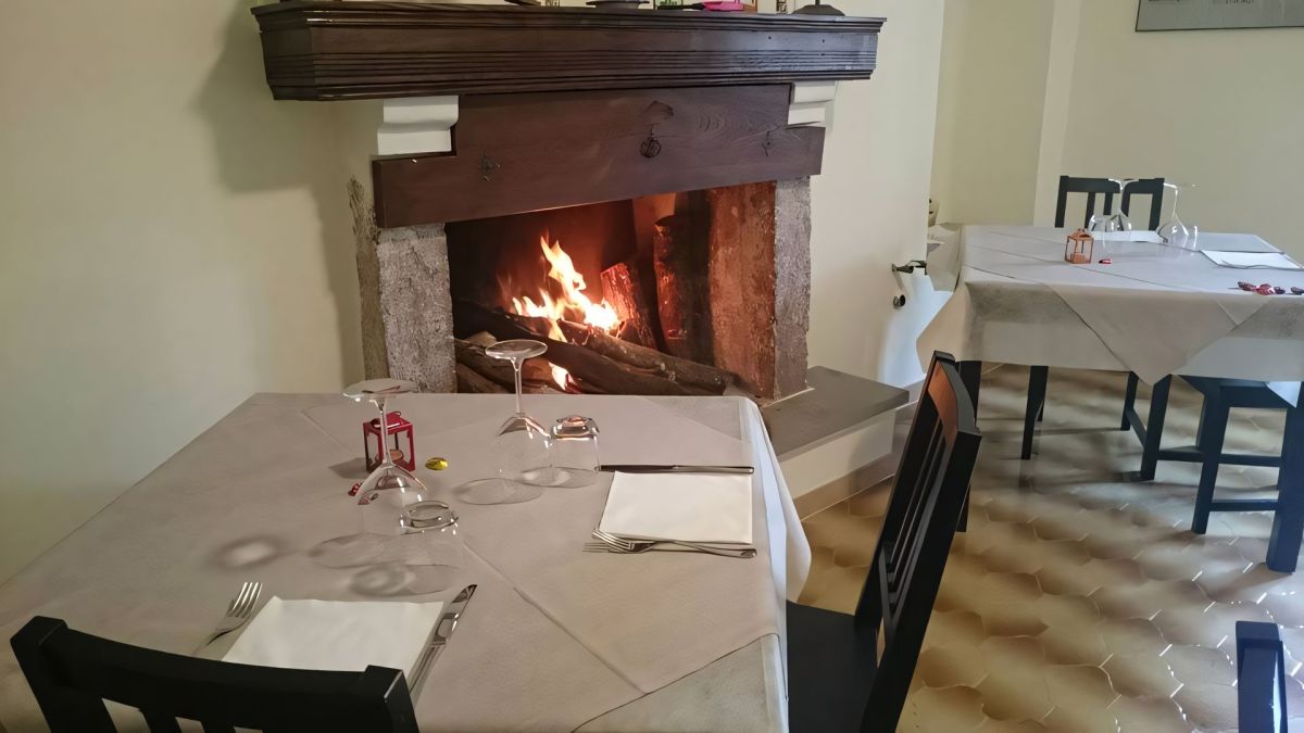 Cozy restaurant with a lit fireplace, well-set tables, and a welcoming atmosphere.