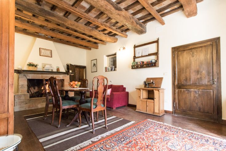 Soggiorno accogliente con tavolo da pranzo, divano, travi a vista e camino.