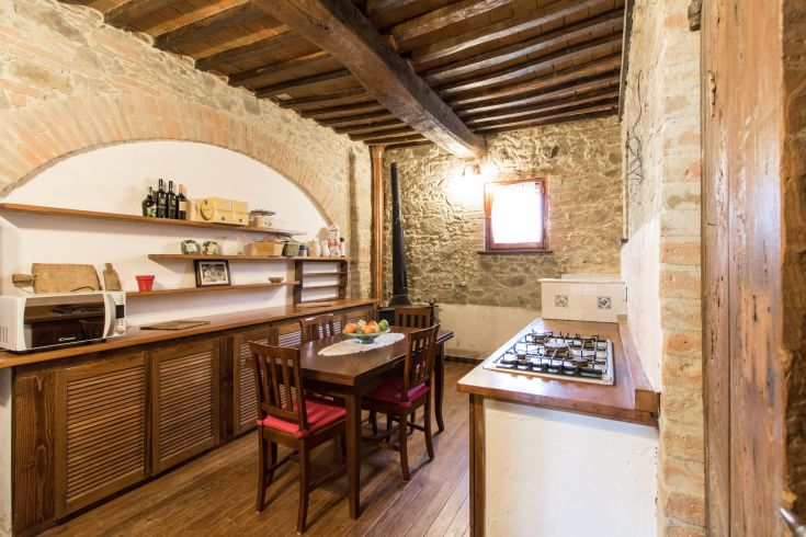 Cucina semplice e accogliente, con tavolo in legno e decorazioni tipiche di un ambiente rurale.