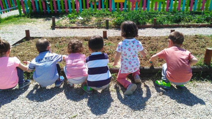 Due bambini che si dedicano alla cura dell'orto in un giorno di sole.