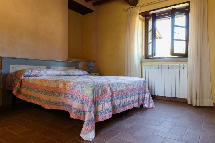 Einfaches Zimmer mit einem Doppelbett und Blick auf die umgebende Natur, perfekt für einen ruhigen Aufenthalt.