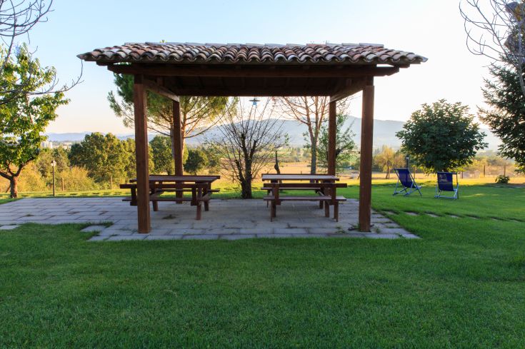 Ein ruhiger Bereich mit einem Pavillon und Tischen, umgeben von grünen Pflanzen.