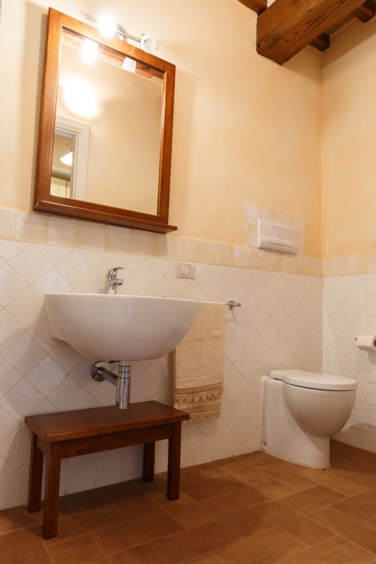 Ein einfaches Badezimmer mit einem zeitgenössischen Waschbecken und einem Holzkanten spiegel.