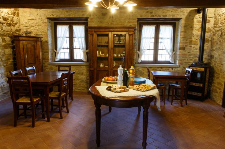 Geräumiger Speisesaal in einem Agriturismo mit Holztischen und einfachen rustikalen Möbeln.