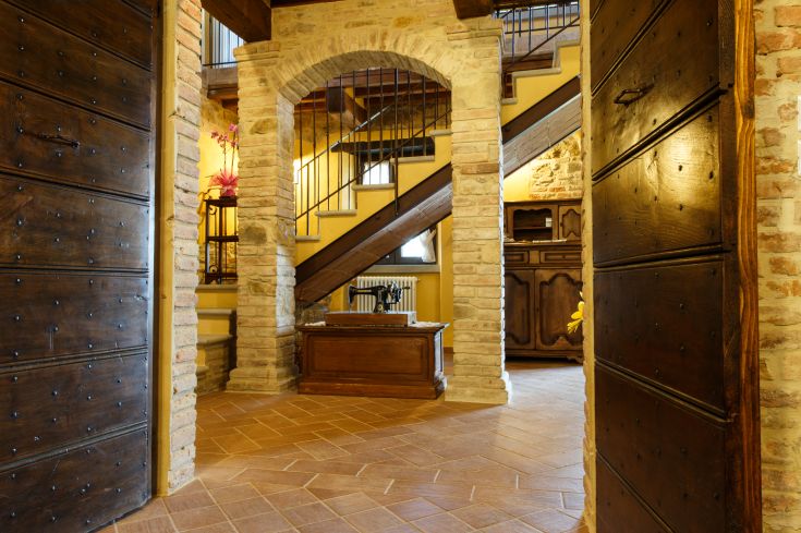 Eingang einer Ferienwohnung mit Holztreppe und sichtbarem Backstein, in einer einfachen Umgebung.