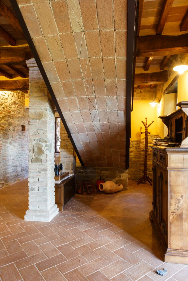 Innenraum eines Agriturismo mit Terrakotta-Decken und Steinelementen, warmes und rustikales Ambiente.