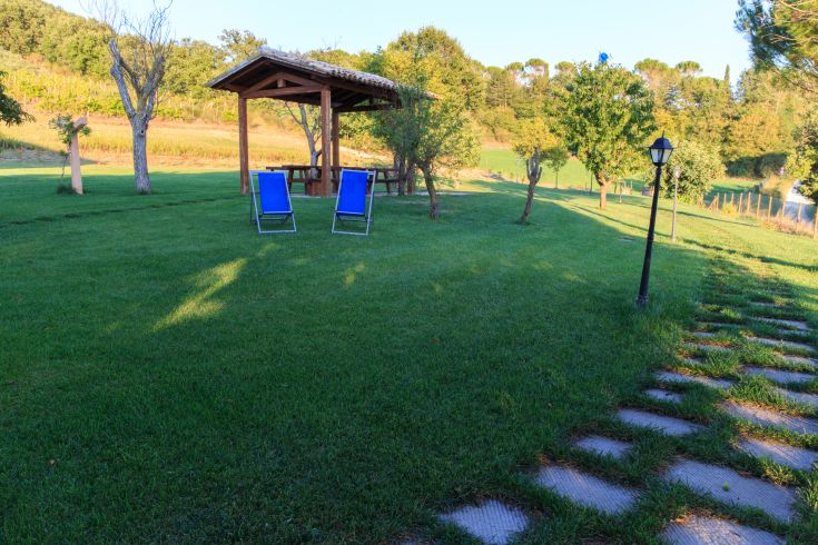 Ein ruhiger grüner Bereich mit einem Pavillon, Liegestühlen und Wegen, ideal für eine entspannende Pause im Freien.