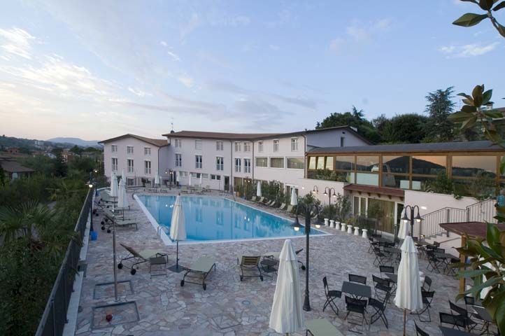 Une piscine entourée de verdure, équipée de chaises longues et de parasols.