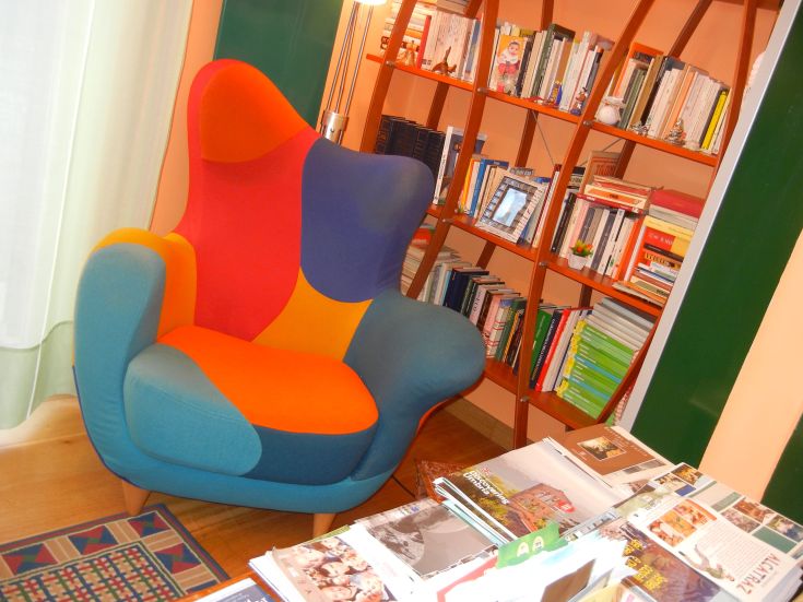 Un fauteuil coloré et confortable dans un environnement tranquille, entouré d'étagères et d'accessoires cosy.