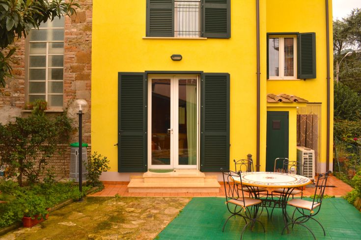 Une maison colorée avec un jardin, idéale pour un séjour serein et relaxant.