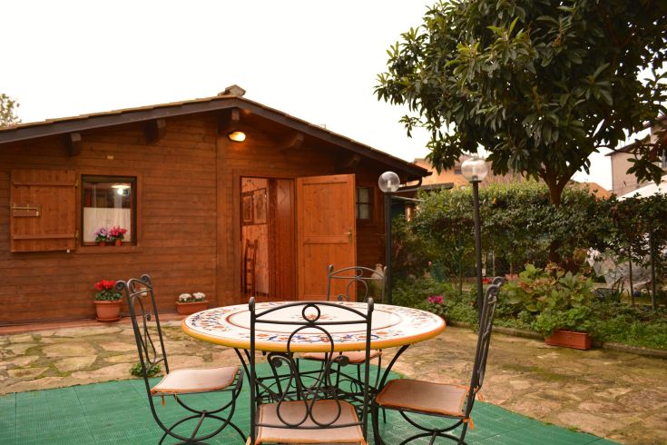 Une maison en bois avec une table extérieure, entourée d'un jardin vert et paisible.
