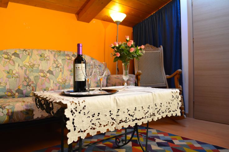 Un salon simple avec une table décorée d'une bouteille de vin, de verres et de fleurs, idéal pour un moment de sérénité.