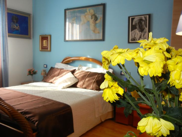 Chambre simple avec des décorations sobres et des fleurs jaunes, offrant un environnement calme pour un séjour relaxant.