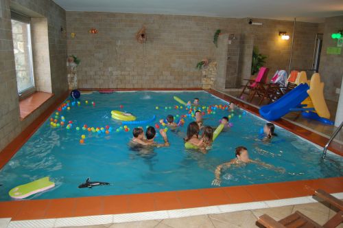 A group of children plays and enjoys in an indoor pool featuring inflatable games.