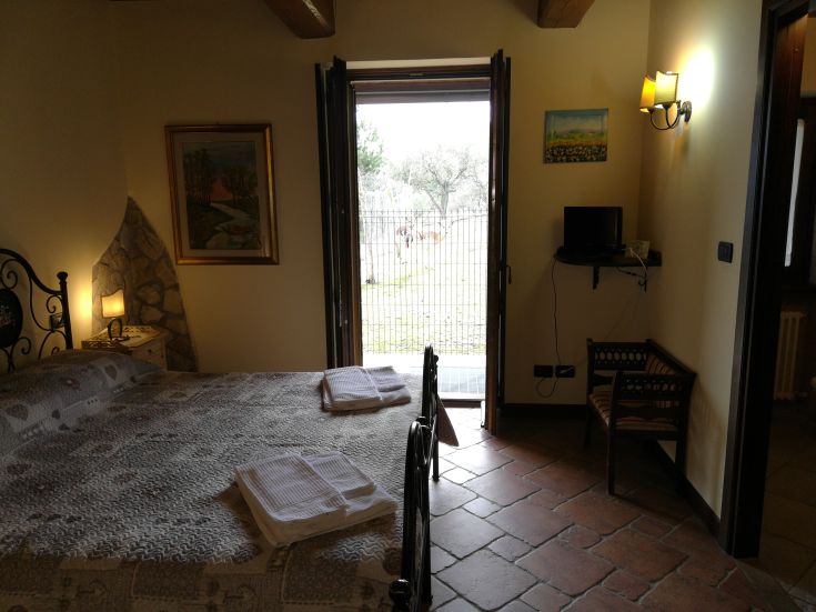 Gemütliches Gästezimmer mit Blick auf das umliegende Grün, einfach und gut gepflegt eingerichtet.