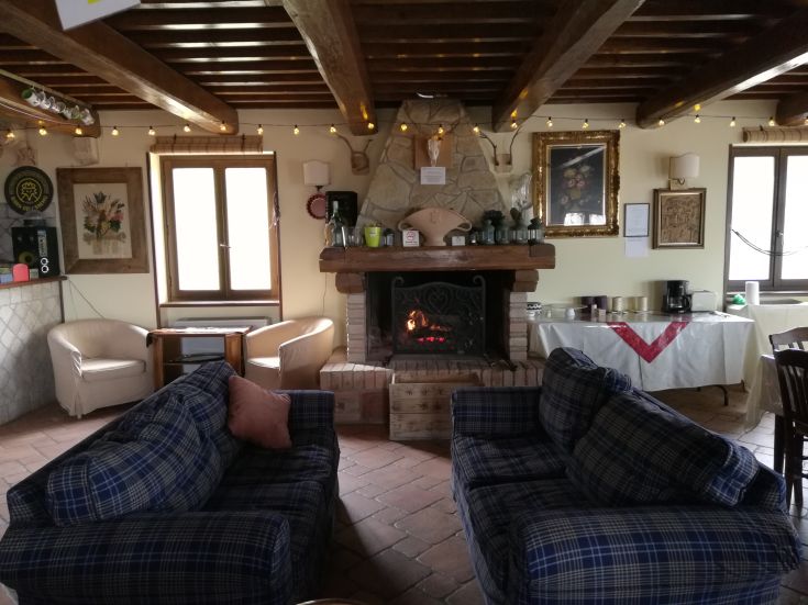 Geräumiges Wohnzimmer auf einem Bauernhof mit einem Kamin, karierten Sofas und rustikalen Dekorationen.