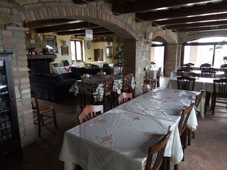 Ein einfaches Esszimmer in einem Bauernhaus mit eingedeckten Tischen und Blick auf die umliegende Landschaft.