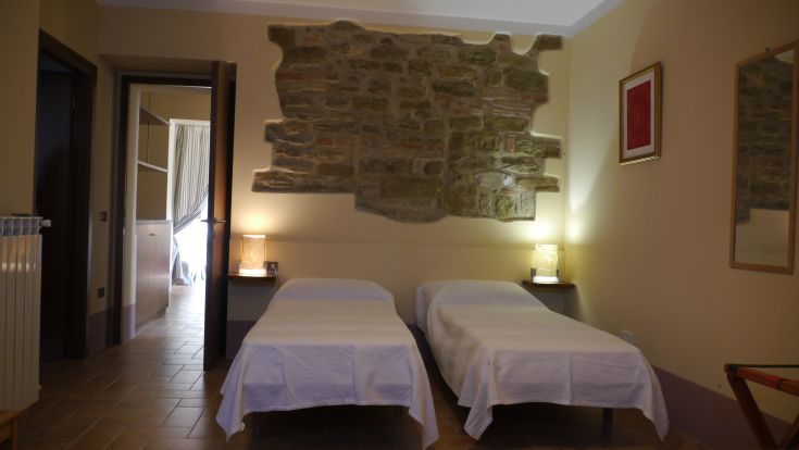 A rustic agriturismo room with simple decorations and stone walls.