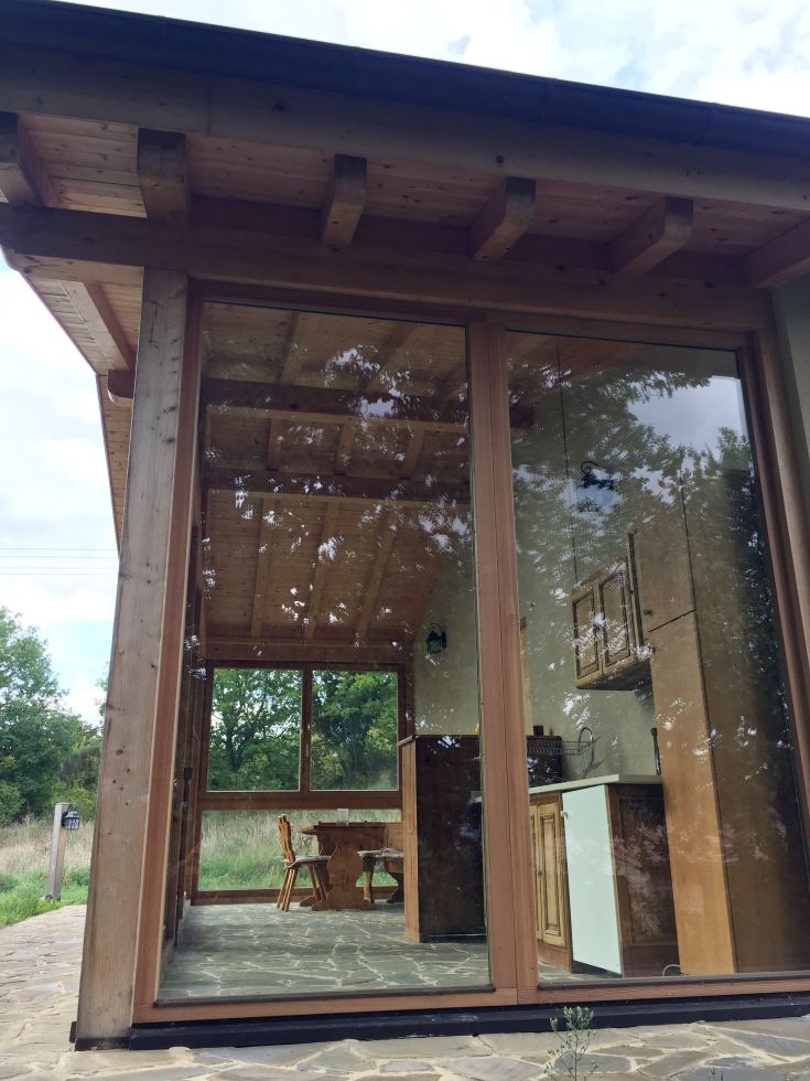 Wooden interior scene with large windows, surrounded by nature.