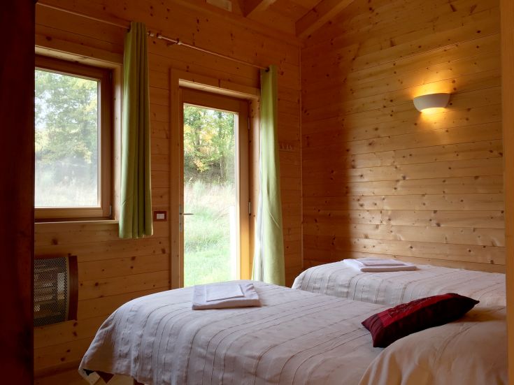 Cozy wooden room overlooking a green area with simple furnishings.