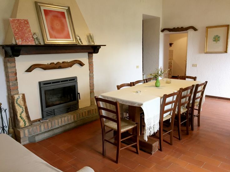 Spacious dining room with a fireplace and a large table for gatherings in a farmhouse.