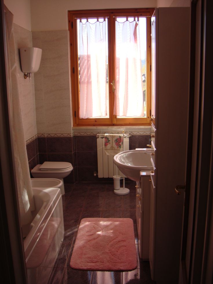 Modern bathroom with natural light featuring a bathtub and fixtures in a simple, contemporary environment.